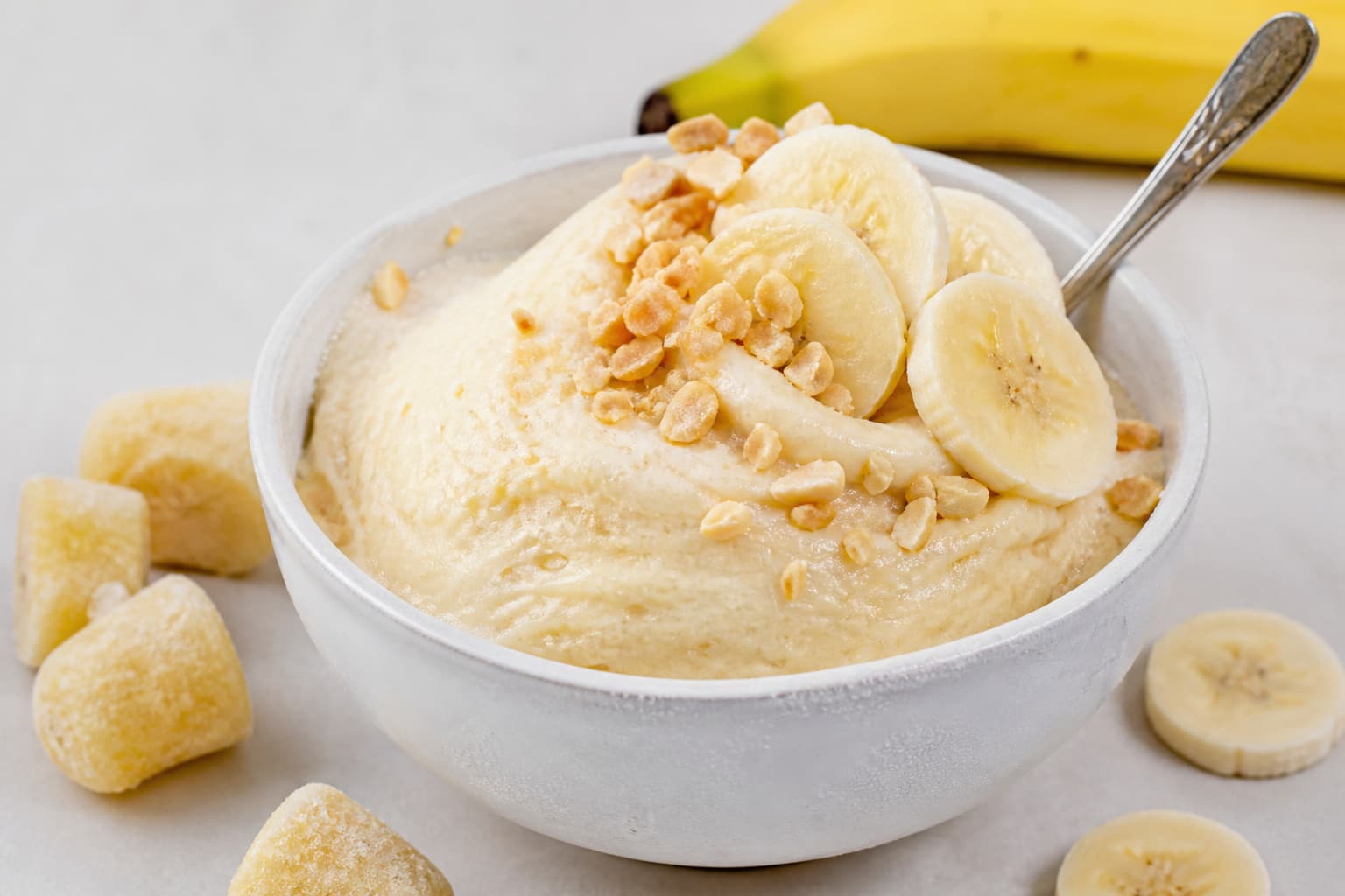 Une boule de crème glacée à la banane dans un bol froid, de texture lisse, surmontée de rondelles de banane et d