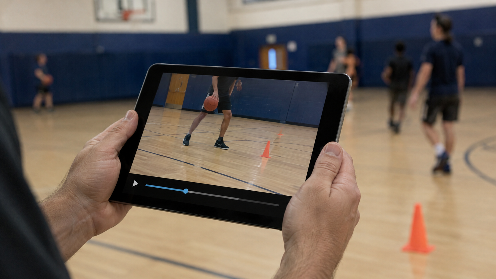 Mains d’un enseignant tenant une tablette au bord d’un gymnase, écran d’une capsule courte avec timeline, silhouettes floues et plot orange.